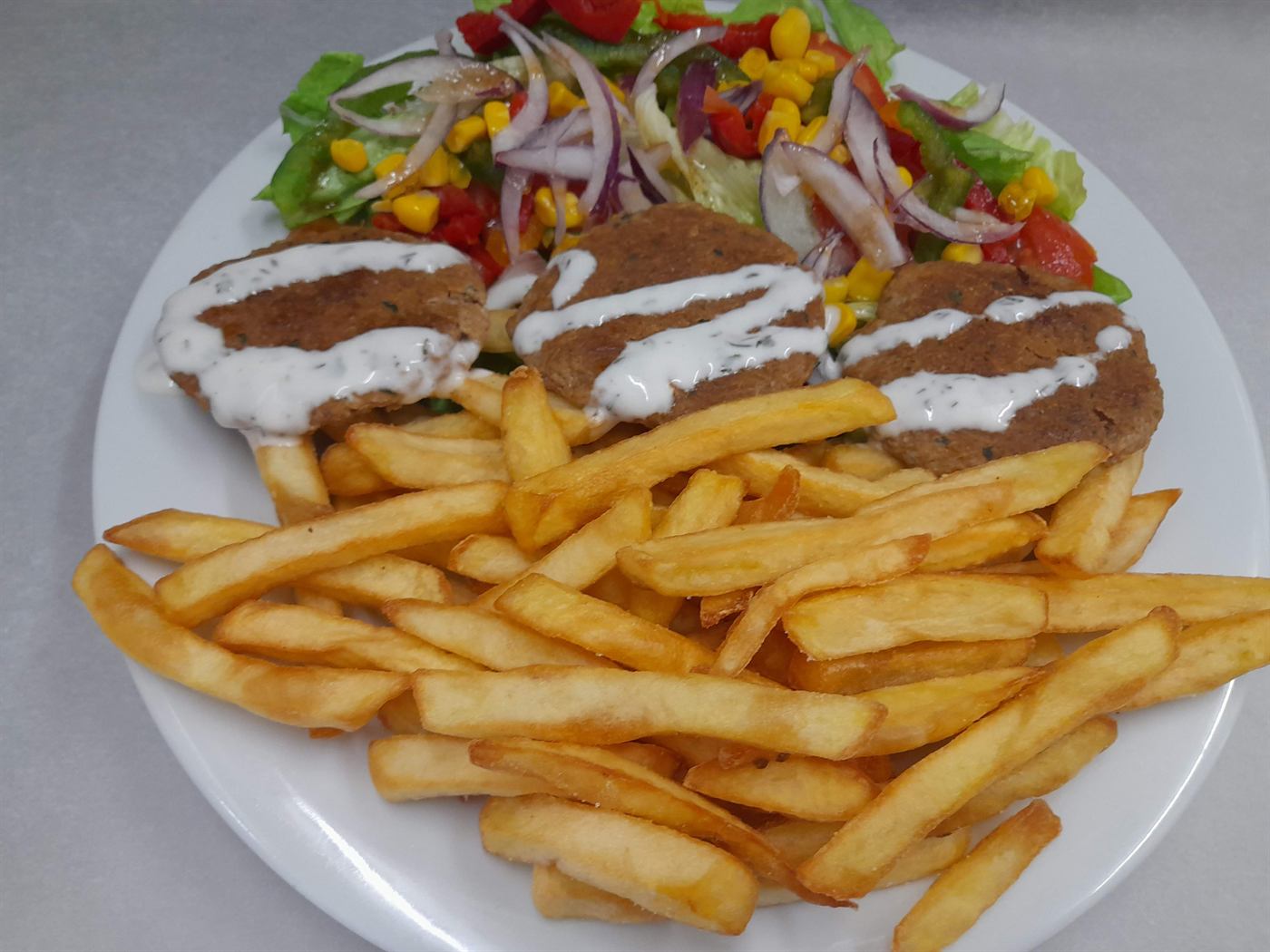 Assiette de galettes panées, frites et salade colorée