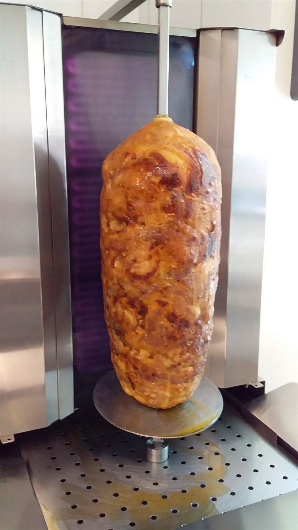 Broche de kebab maison en train de tourner derrière le comptoir
