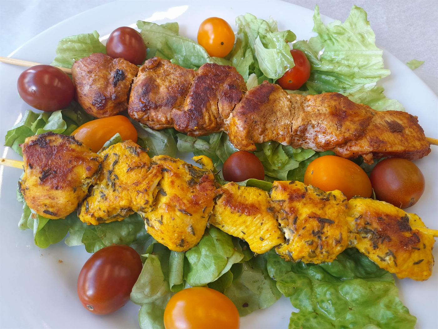 Brochettes de poulet mariné sur salade et tomates cerises