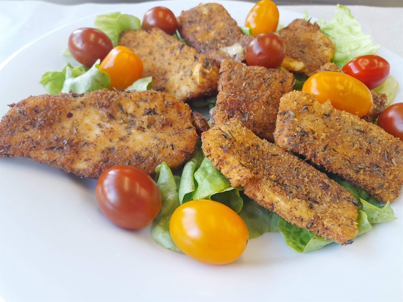 Tenders de poulet croustillants sur salade et tomates multicolores