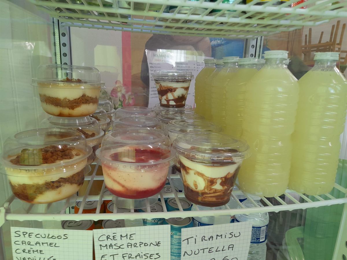 Verrines de desserts maison et bouteilles de citronnade dans la vitrine